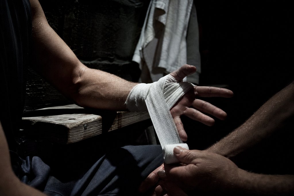 Die Hände eines Boxers werden in der Kabine bandagiert, nur Unterarme und Bandage im Bild